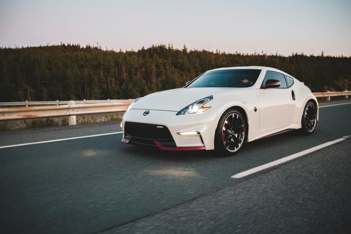 A white sports coupe on an open road at dusk