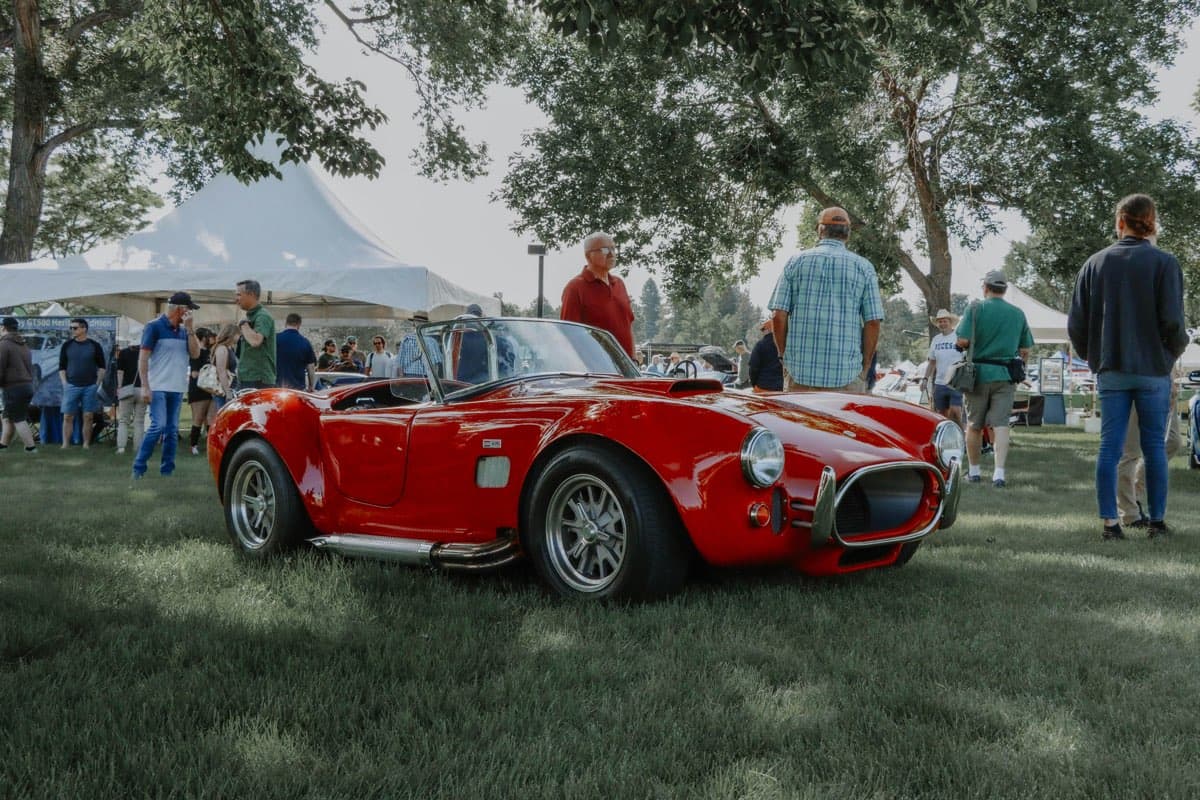 A red Cobra roadster on the lawn at a show and shine